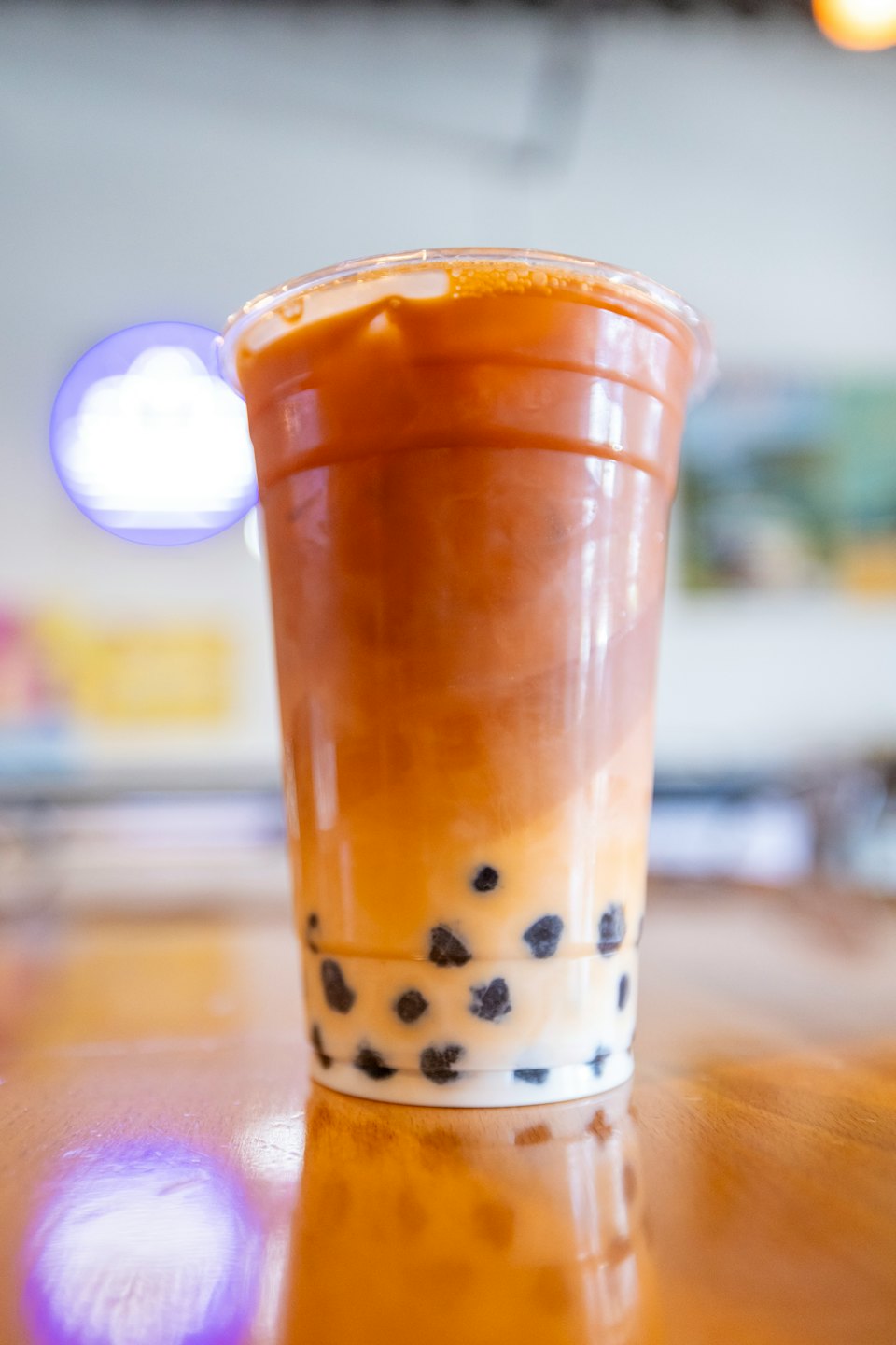 Bubble tea with tapioca pearls sits on a wooden table.