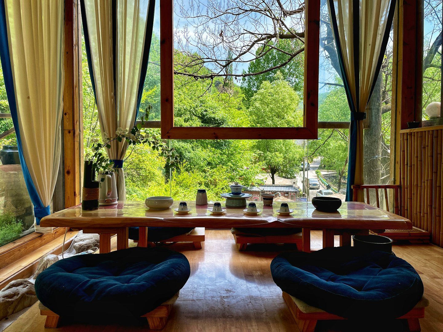 Tea set on a wooden table between two floor cushions.