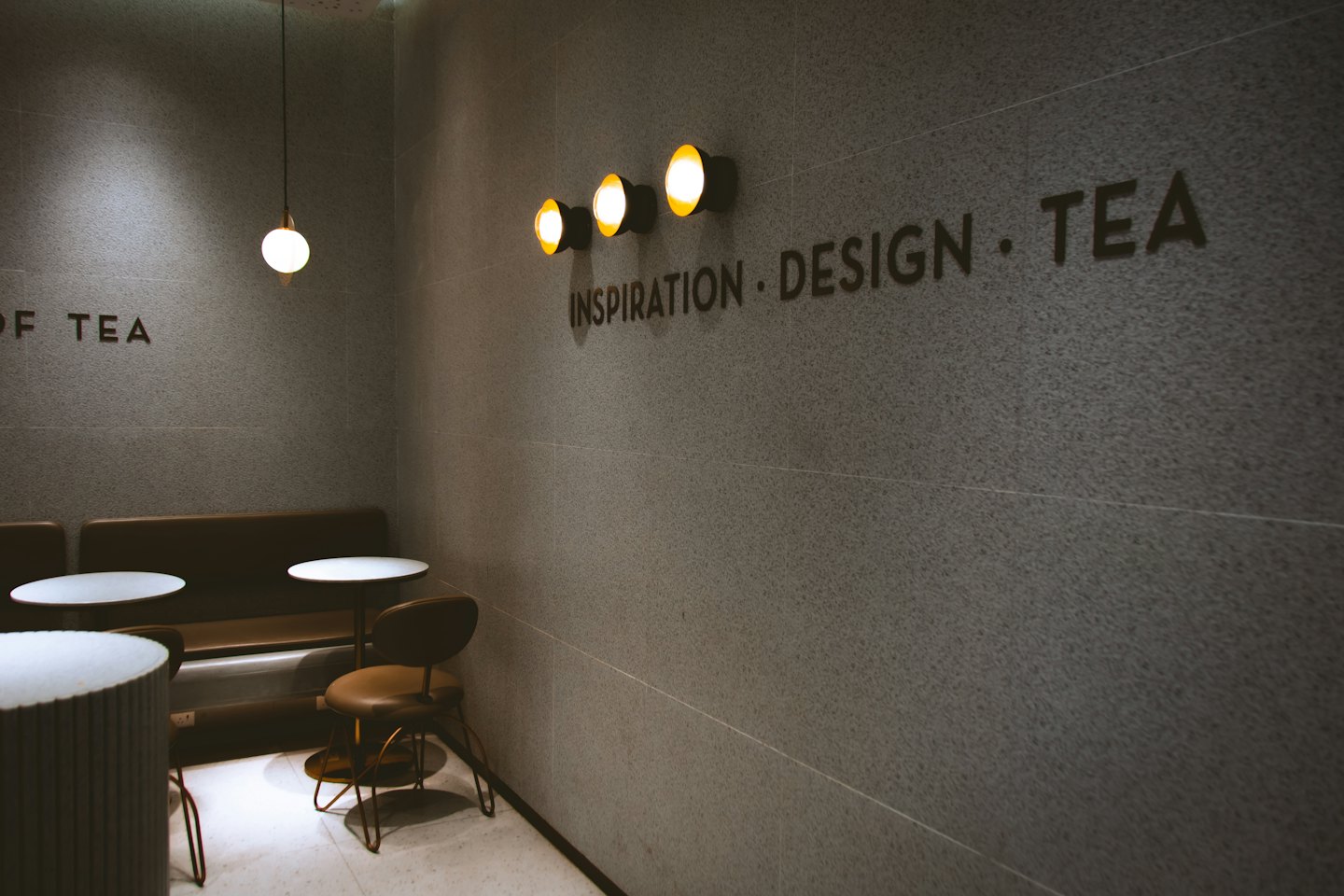 Modern cafe interior with leather banquettes and white tables.