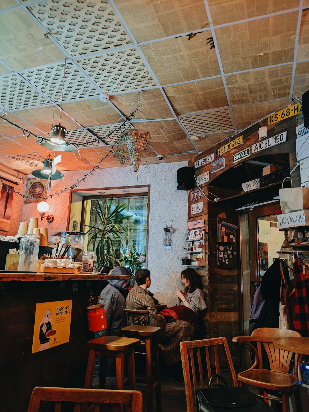 Three customers talk while seated at tables in a cafe.
