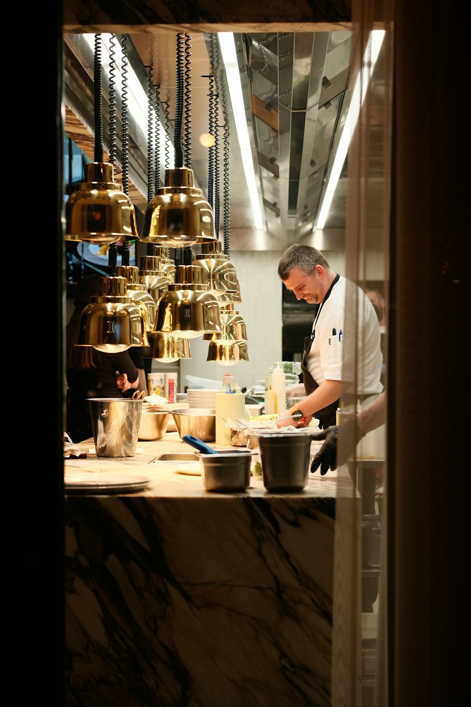 Chef in a white jacket prepares food at a kitchen counter.