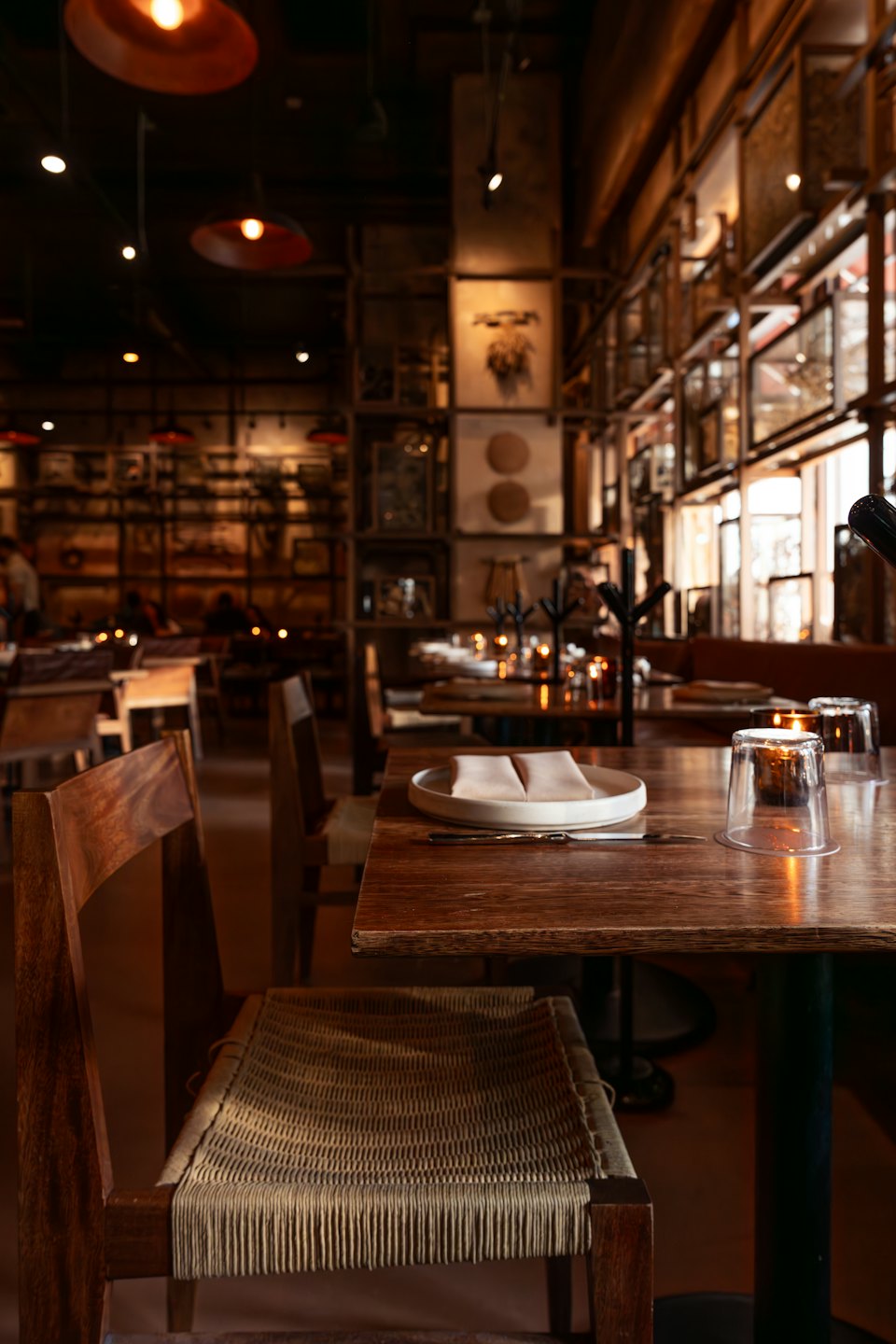 Empty restaurant tables set for dinner with a lit candle.